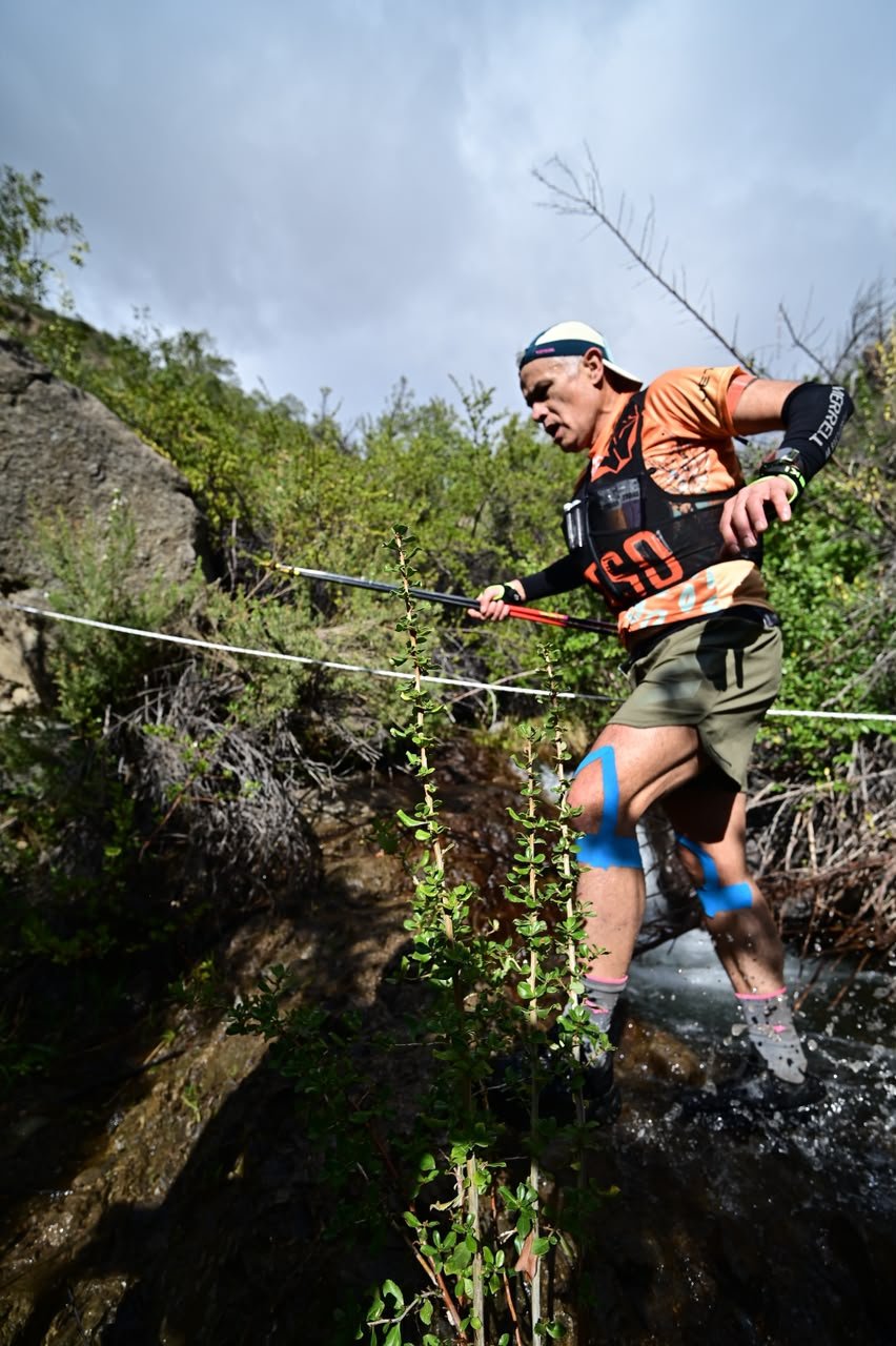 Octavio Muñoz cruzando un arroyo con bastones durante Cascada Trail 21K